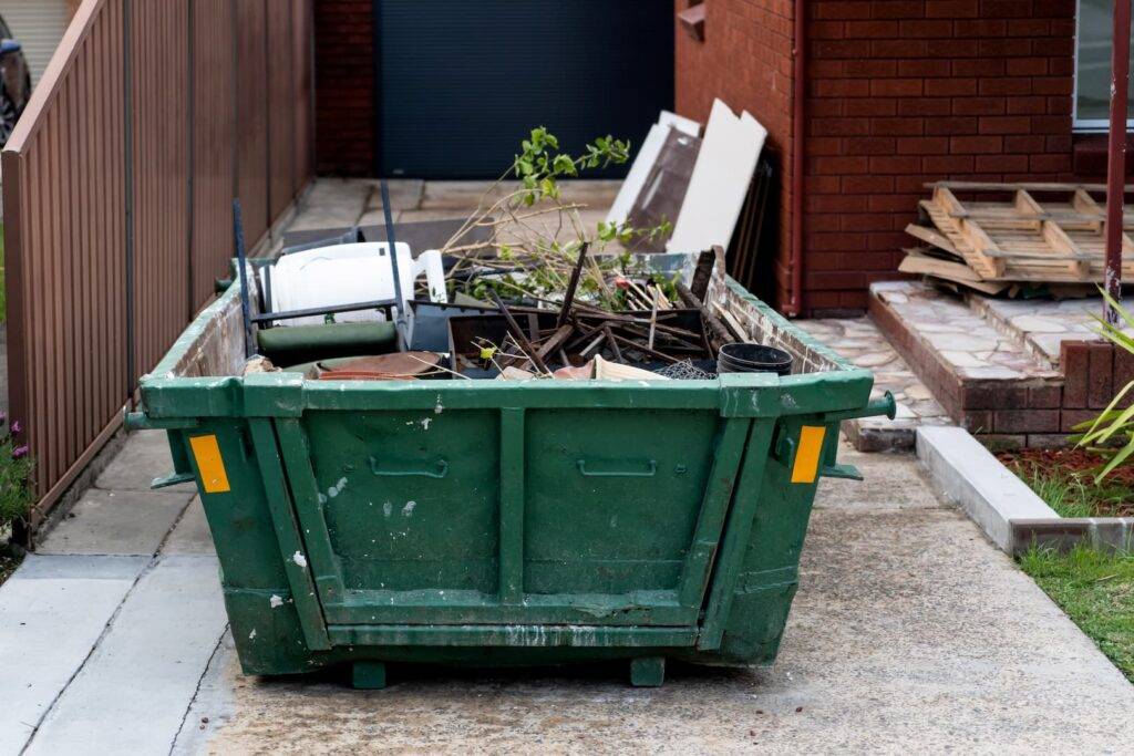 Skip bin with household waste rubbish on a front yard. House clean up concept.